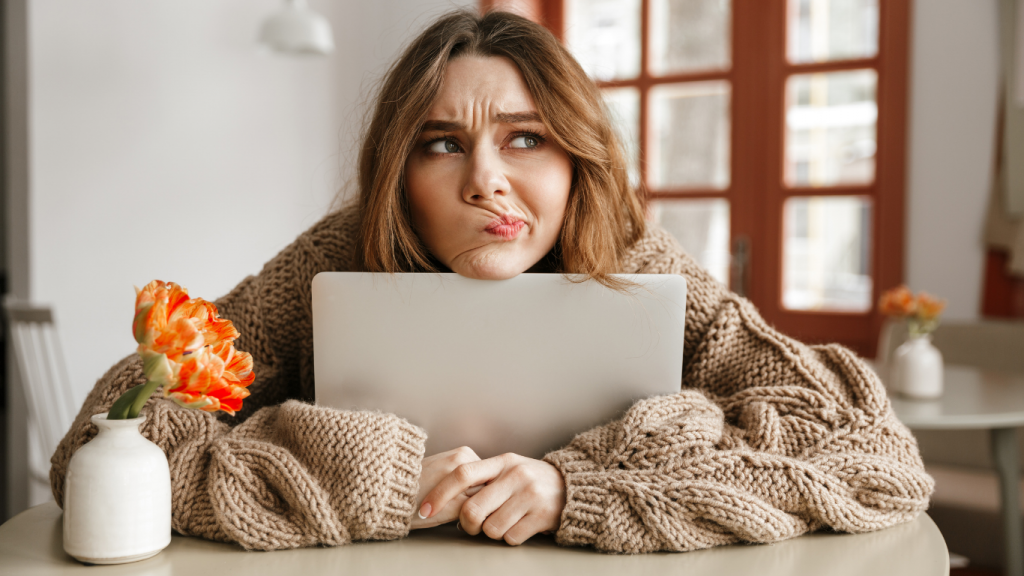 young woman hugging her laptop with an unsure or confused facial expression.