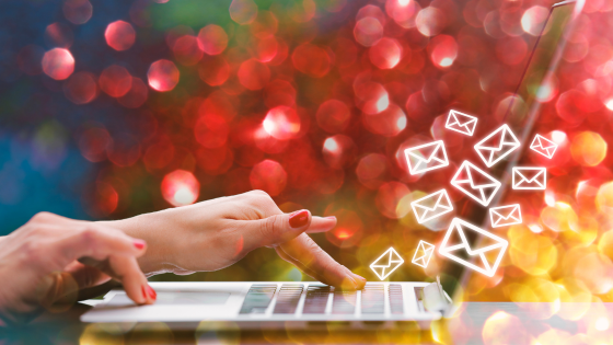 a female hand with red nail polish types on a laptop keyboard and images of envelopes float into the screen - - grow your email list hero image